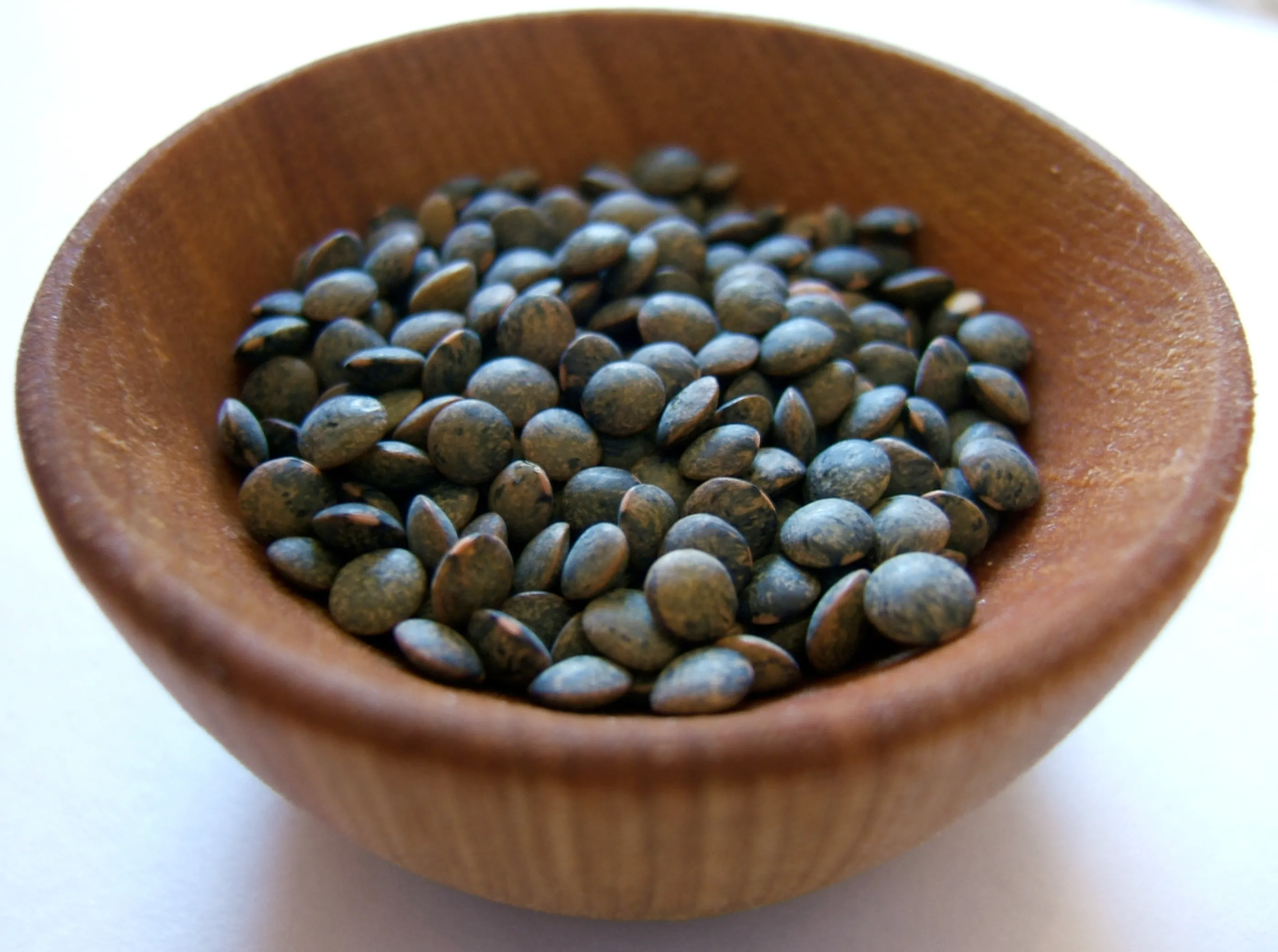 A wooden bowl of Puy lentils